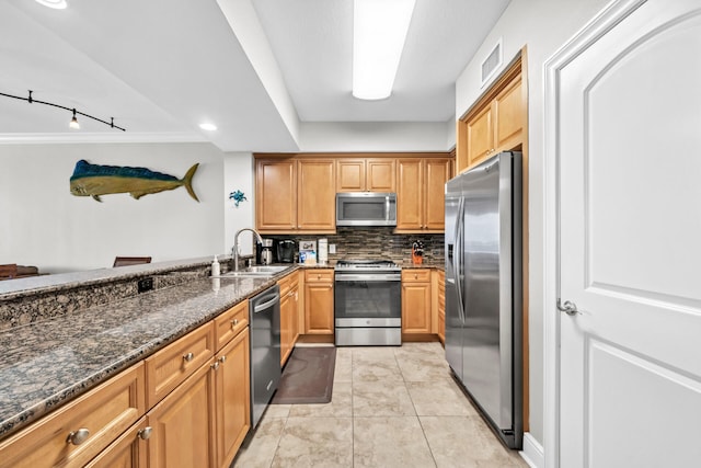 kitchen with visible vents, decorative backsplash, a sink, dark stone countertops, and appliances with stainless steel finishes