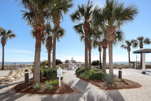 surrounding community with a water view and fence