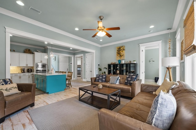 living area with ceiling fan, recessed lighting, light wood-style floors, ornamental molding, and baseboards