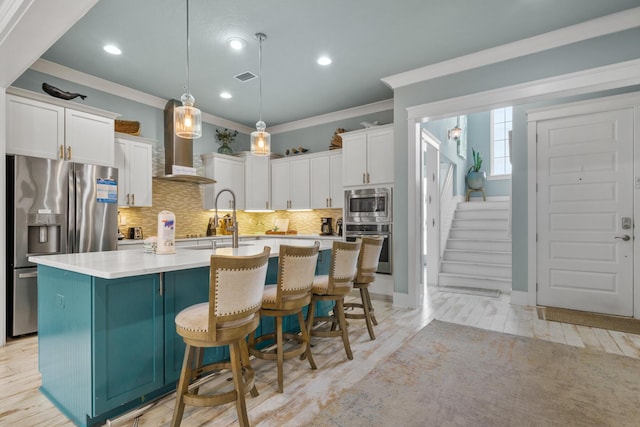 kitchen with stainless steel appliances, ornamental molding, white cabinetry, wall chimney exhaust hood, and backsplash