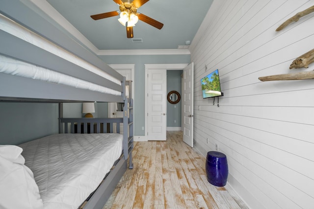 bedroom featuring wood walls, wood finished floors, ceiling fan, and ornamental molding