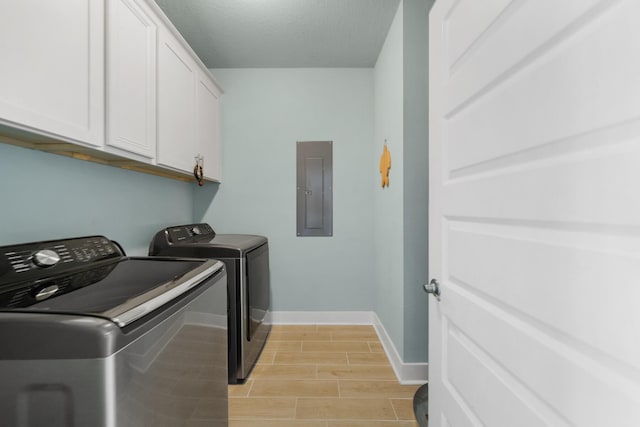 clothes washing area with electric panel, washer and dryer, cabinet space, baseboards, and wood finish floors