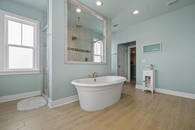 full bathroom with a shower stall, healthy amount of natural light, wood finished floors, and recessed lighting