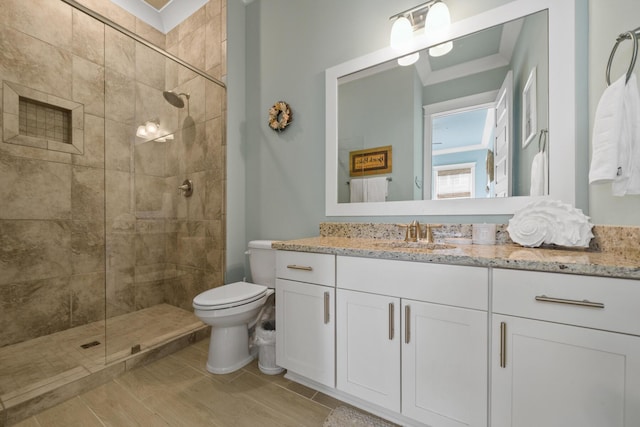 bathroom with tiled shower, toilet, vanity, and wood finished floors