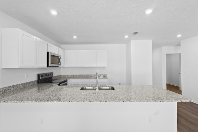 kitchen with a sink, appliances with stainless steel finishes, recessed lighting, and light stone counters