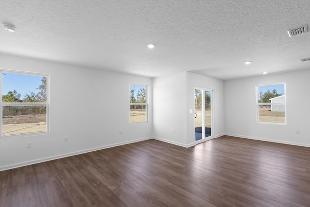 empty room featuring a textured ceiling, visible vents, baseboards, dark wood-style floors, and recessed lighting