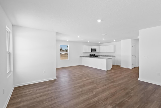 unfurnished living room with a sink, baseboards, dark wood-style flooring, and recessed lighting
