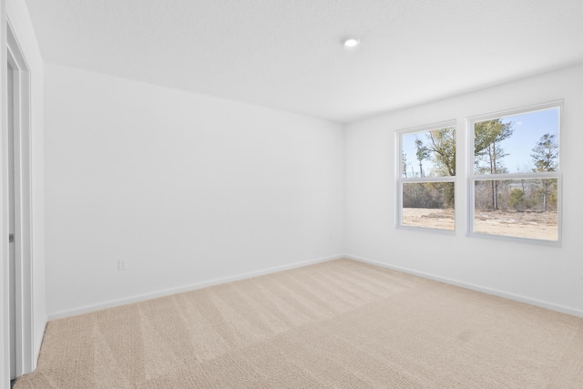 empty room featuring baseboards, light carpet, and recessed lighting