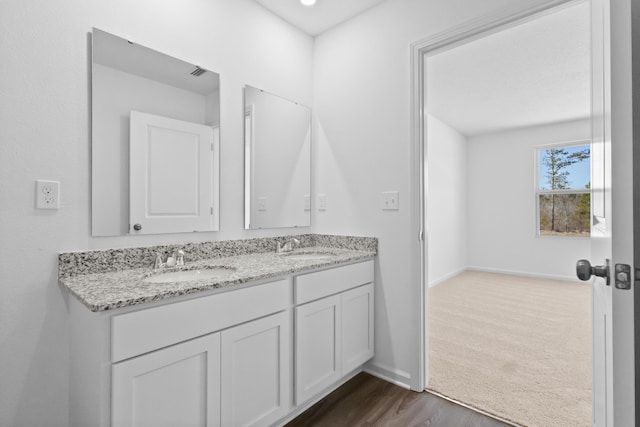 bathroom with double vanity, baseboards, a sink, and wood finished floors