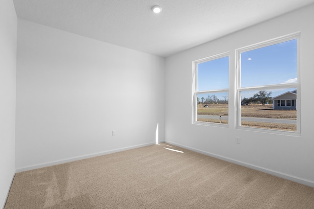 carpeted spare room featuring baseboards