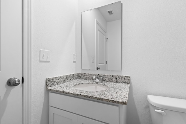 bathroom with vanity, toilet, and visible vents