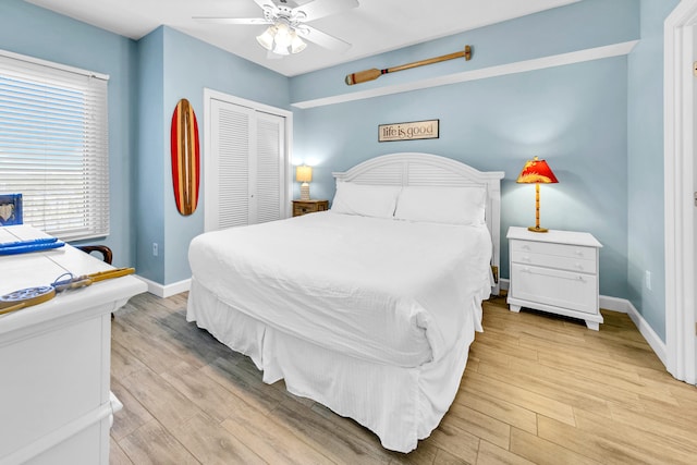 bedroom featuring light wood finished floors, ceiling fan, baseboards, and a closet