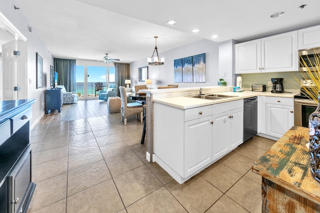 kitchen featuring a sink, open floor plan, a peninsula, decorative backsplash, and stainless steel appliances