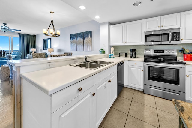 kitchen with a sink, open floor plan, light countertops, appliances with stainless steel finishes, and tasteful backsplash