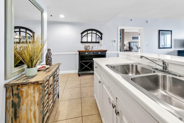 kitchen with light tile patterned flooring, a sink, open floor plan, light countertops, and white cabinets