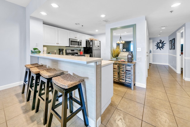 kitchen with light tile patterned floors, light countertops, stainless steel appliances, and a peninsula