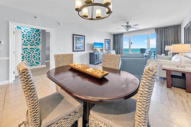 dining area with light tile patterned floors, baseboards, and ceiling fan with notable chandelier