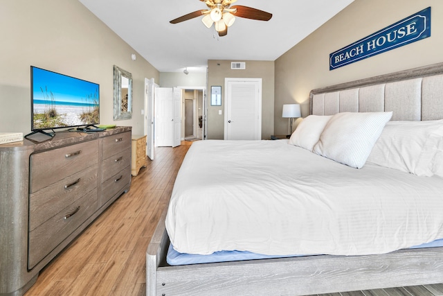 bedroom featuring light wood finished floors, visible vents, and a ceiling fan