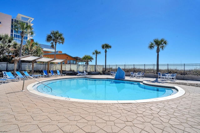 community pool with a patio and fence