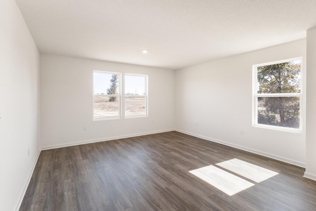 unfurnished room with baseboards and dark wood-style floors