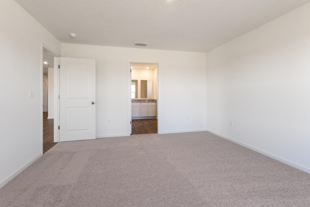 unfurnished bedroom with connected bathroom, baseboards, visible vents, and carpet