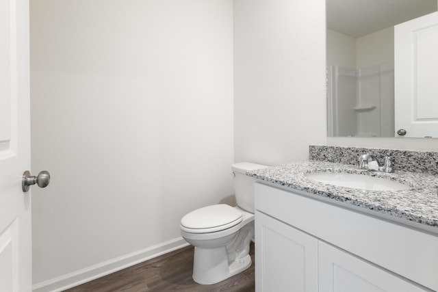 bathroom featuring vanity, baseboards, wood finished floors, and toilet