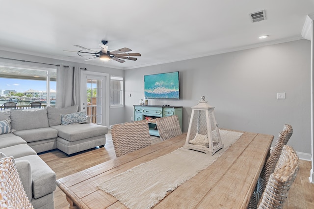 living area with visible vents, ornamental molding, ceiling fan, a water view, and light wood finished floors