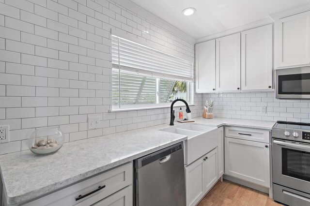 169 Durango Rd, Destin, FL 32541 - kitchen with backsplash, light stone countertops, a sink, stainless steel appliances, and white cabinetry