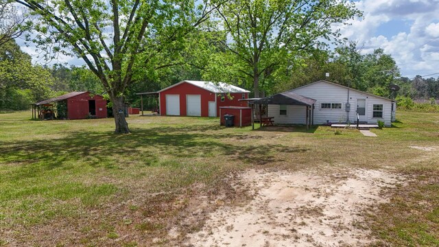 258 Briar Rd, Defuniak Springs, FL 32433 - view of grassy yard featuring a detached garage, an outbuilding, and view of scattered trees