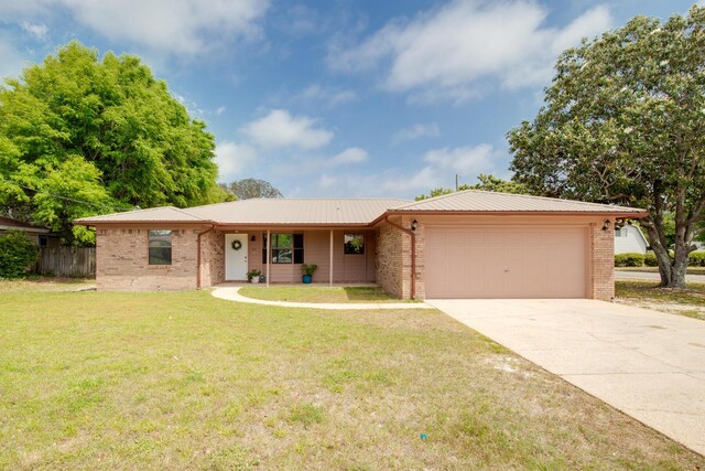 single story home featuring an attached garage, concrete driveway, a front lawn, and brick siding