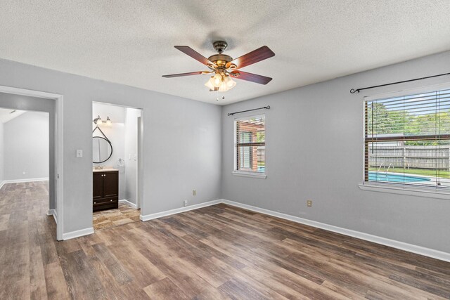 unfurnished bedroom with a textured ceiling, wood finished floors, and multiple windows