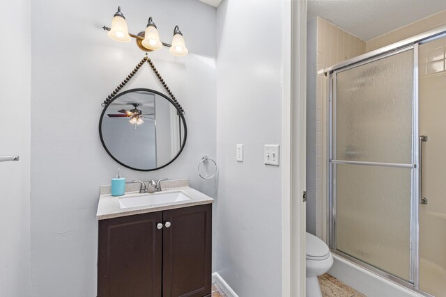 full bath with vanity, a ceiling fan, toilet, and a stall shower