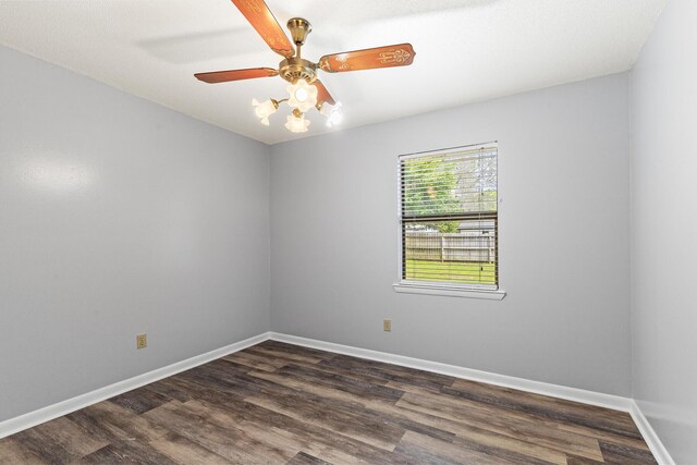 empty room featuring baseboards, a ceiling fan, and dark wood-style flooring