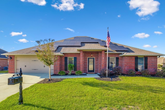 ranch-style house featuring an attached garage, brick siding, a front yard, roof mounted solar panels, and driveway