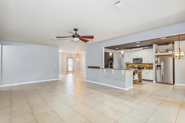 unfurnished living room featuring baseboards, ceiling fan, visible vents, and light tile patterned floors