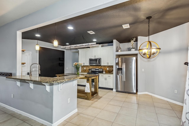 kitchen with backsplash, appliances with stainless steel finishes, light tile patterned floors, stone countertops, and a breakfast bar