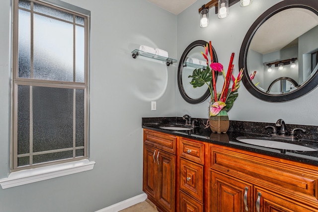 full bath featuring double vanity, a sink, and baseboards