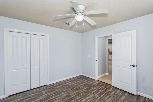 unfurnished bedroom with visible vents, a closet, wood finished floors, baseboards, and ceiling fan