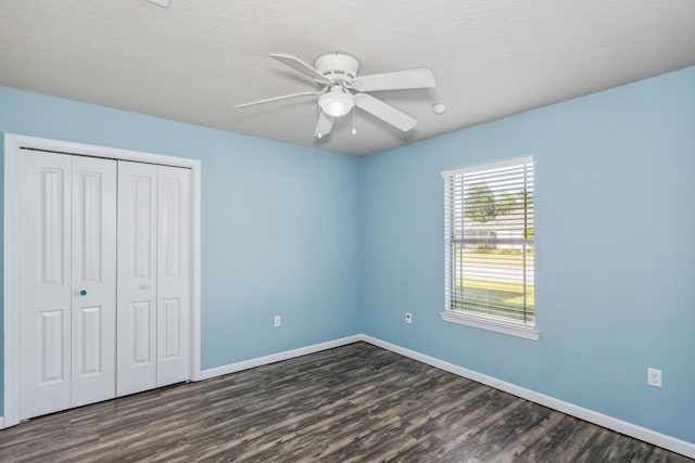 unfurnished bedroom with a ceiling fan, baseboards, dark wood finished floors, and a closet