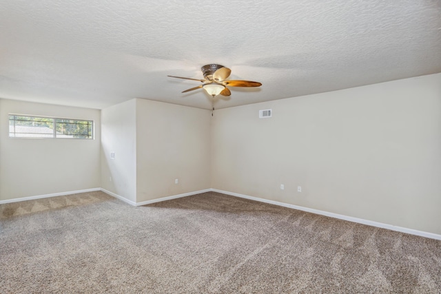 empty room with a ceiling fan, a textured ceiling, visible vents, baseboards, and carpet flooring