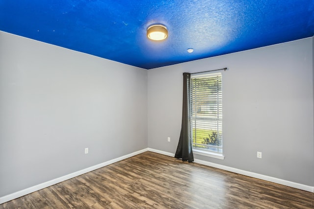 spare room with baseboards and wood finished floors