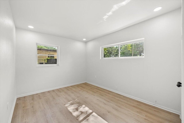 spare room featuring recessed lighting, baseboards, a wealth of natural light, and light wood-style floors
