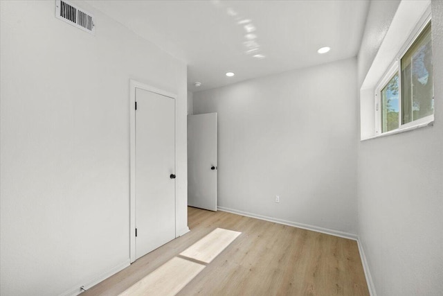 empty room featuring visible vents, recessed lighting, baseboards, and wood finished floors