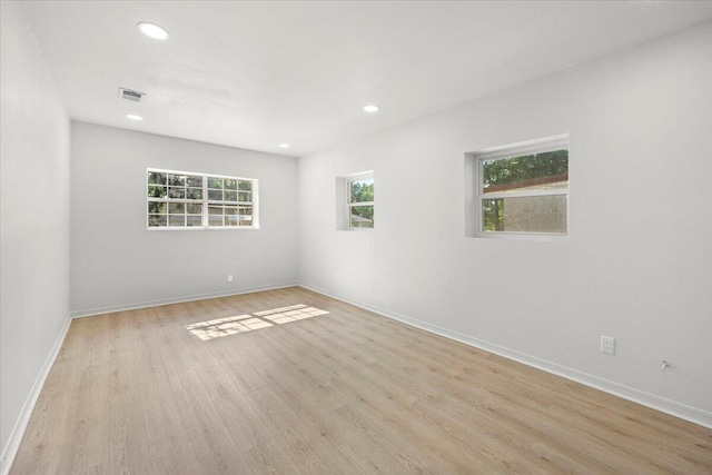 empty room with recessed lighting, baseboards, light wood finished floors, and visible vents
