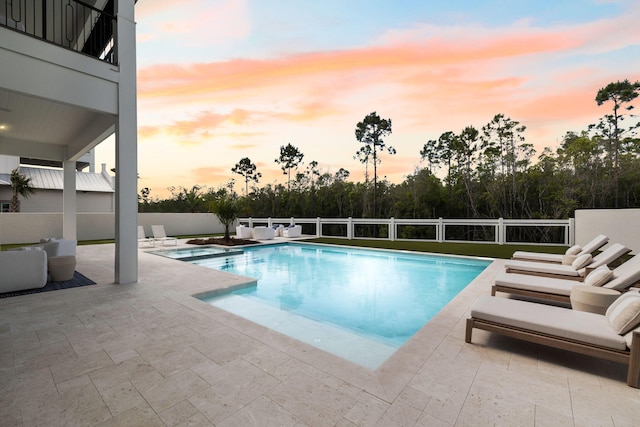 pool at dusk with a fenced in pool, a fenced backyard, and a patio area