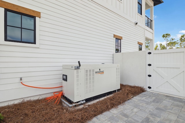 exterior details featuring a gate, board and batten siding, and a power unit