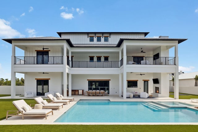 back of property with board and batten siding, a ceiling fan, and a balcony