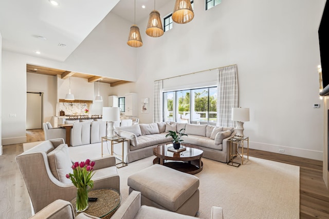 living area with baseboards, recessed lighting, a towering ceiling, and wood finished floors