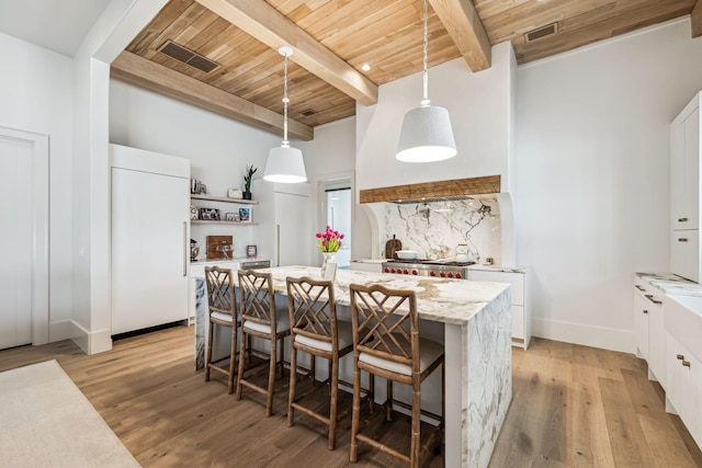 kitchen with beam ceiling, white cabinetry, a kitchen island, refrigerator, and wood ceiling