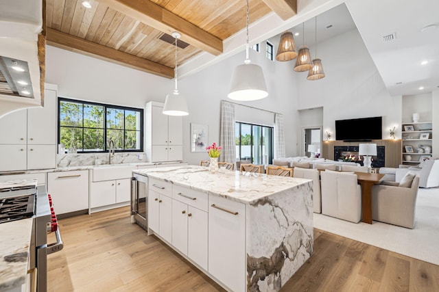kitchen featuring beam ceiling, a center island, high end stainless steel range oven, and light wood-type flooring